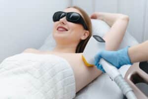 Woman happily receiving laser hair removal treatment to her underarms
