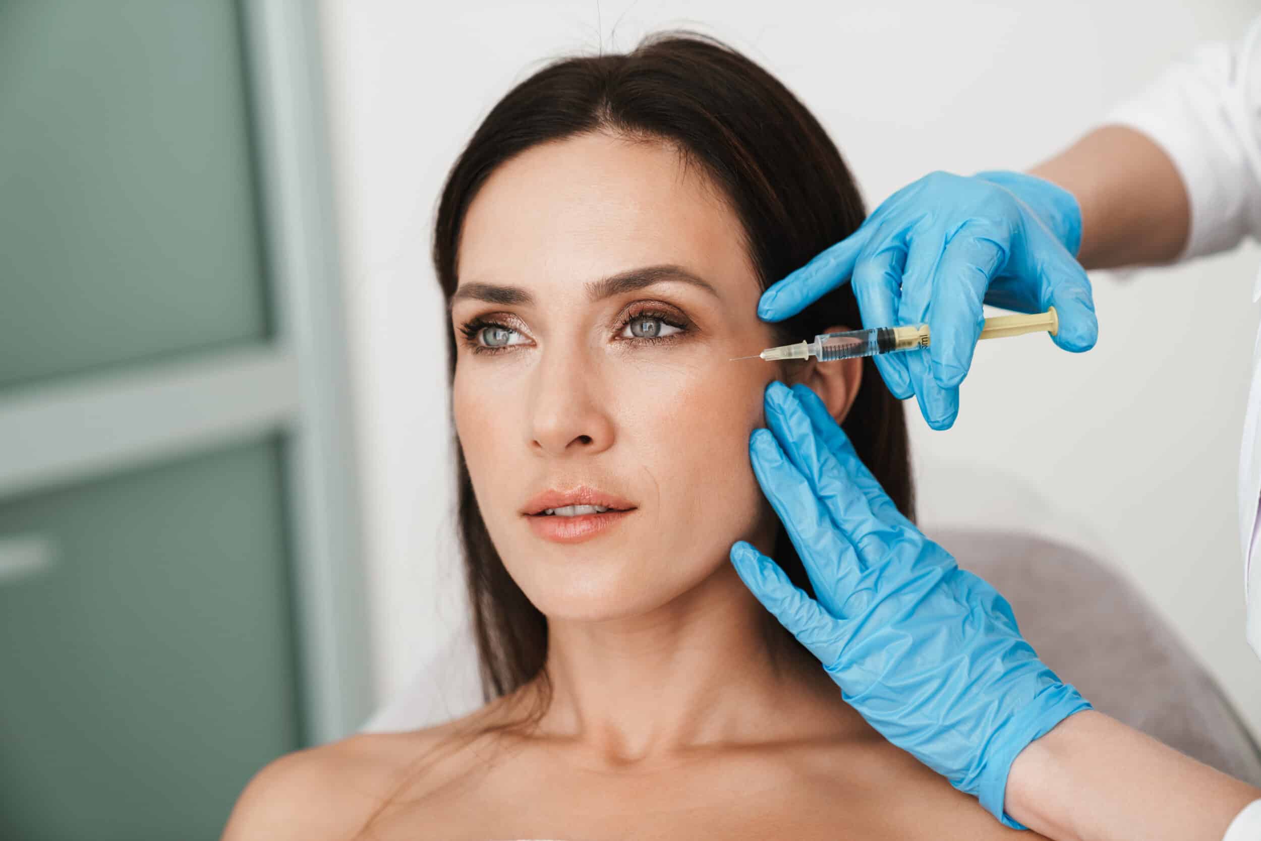 Middle-aged woman getting Daxxify injections around her eyes to reduce fine lines and wrinkles.