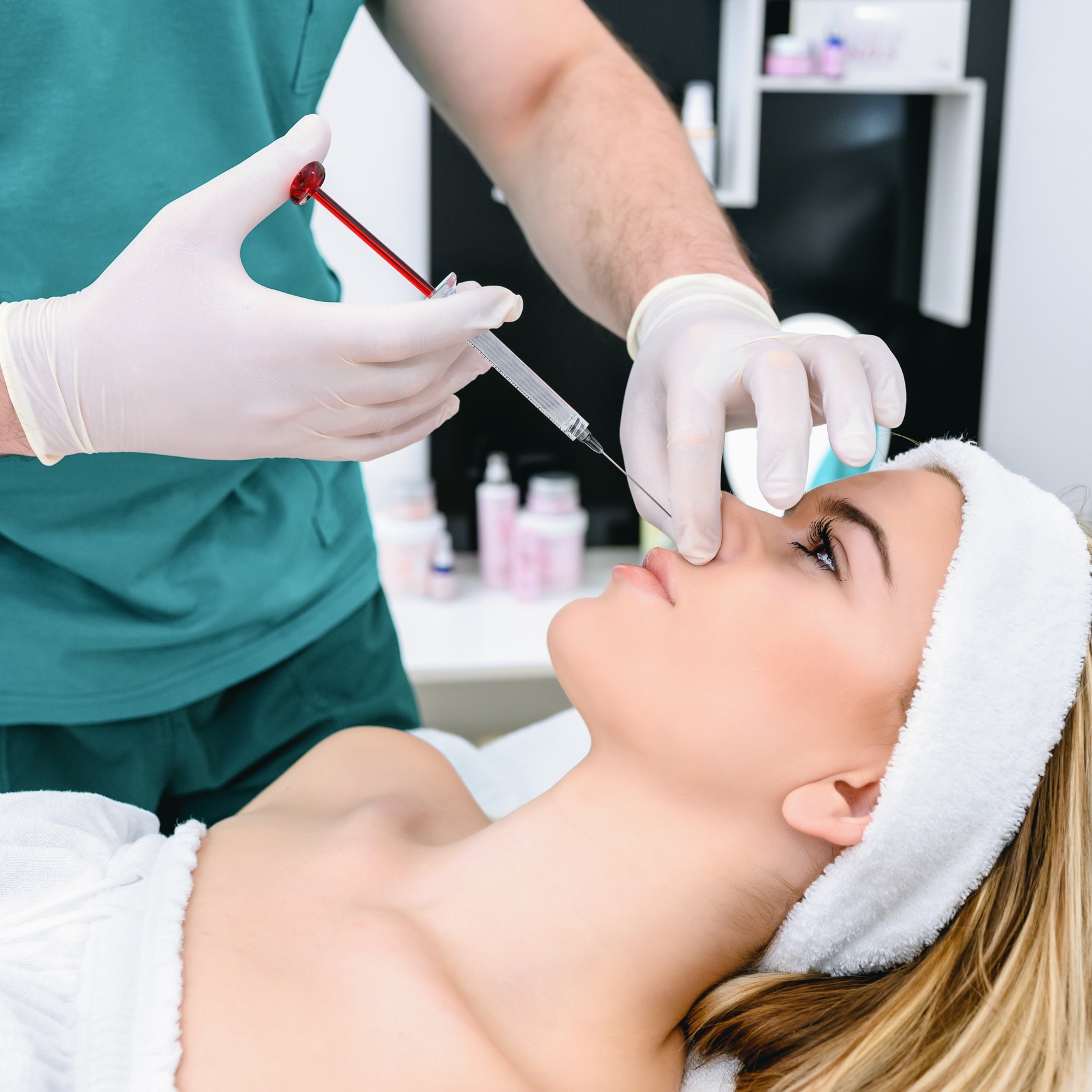 Beautiful young woman receiving Dysport injections around her eyes from her provider to relax wrinkles.