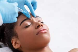 Close up of a beautiful young woman getting Daxxify injections to relax her forehead lines.